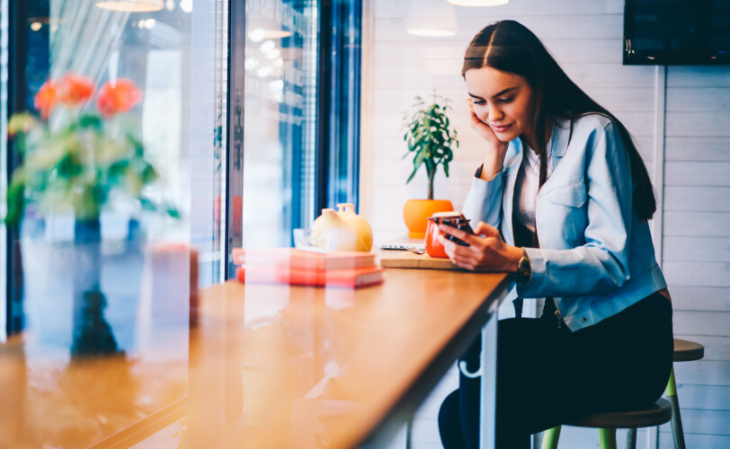 Woman sat at a table looking at her phone.